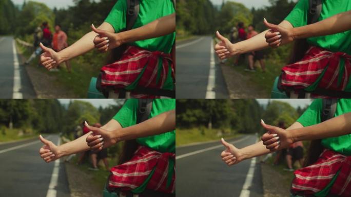 多种族女性双手在山路搭便车时竖起大拇指的特写