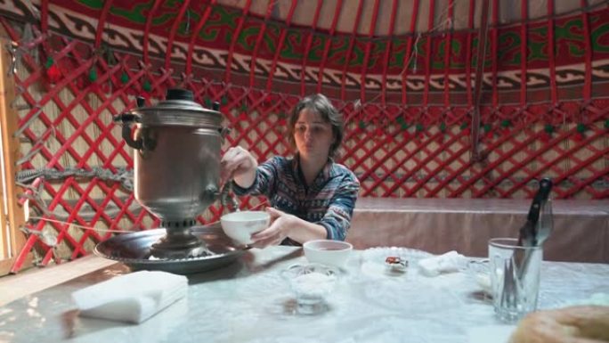 女人在茶炊的蒙古包里喝茶