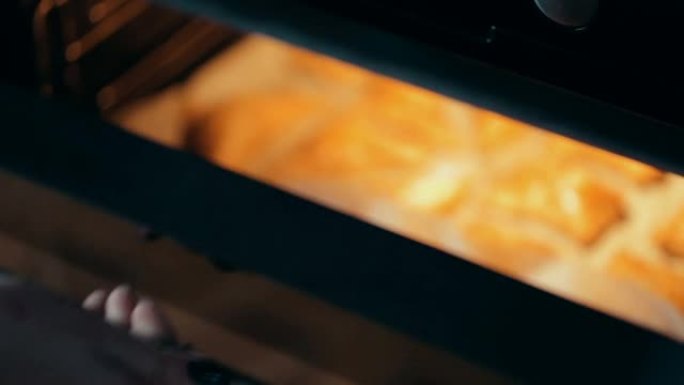 在烤盘上撒上芝麻的美味酥脆酥皮馅饼，上面铺有烘烤羊皮纸。烹饪烘焙的过程。