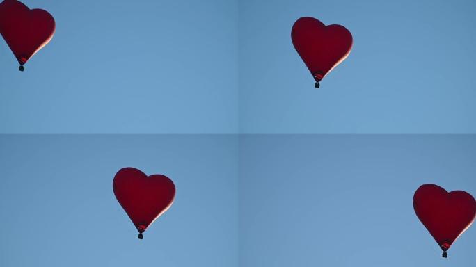彩色热空气心形气球在日落时以慢动作在蓝天上飞行，情人节快乐概念。4k HDR高质量镜头