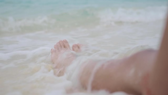 特写棕褐色皮肤女性双腿坐在白色沙滩上，清澈见底的海水，放松夏季热带天堂岛海滩度假，晒伤皮肤，紫外线防