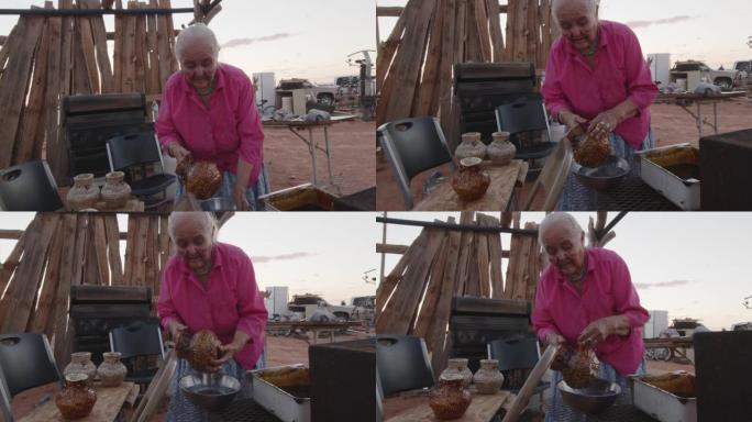 纳瓦霍老年妇女用Pinyon汁液焦油沥青涂在她新编织的篮子上，在室外木炉子上加热，特写视频剪辑