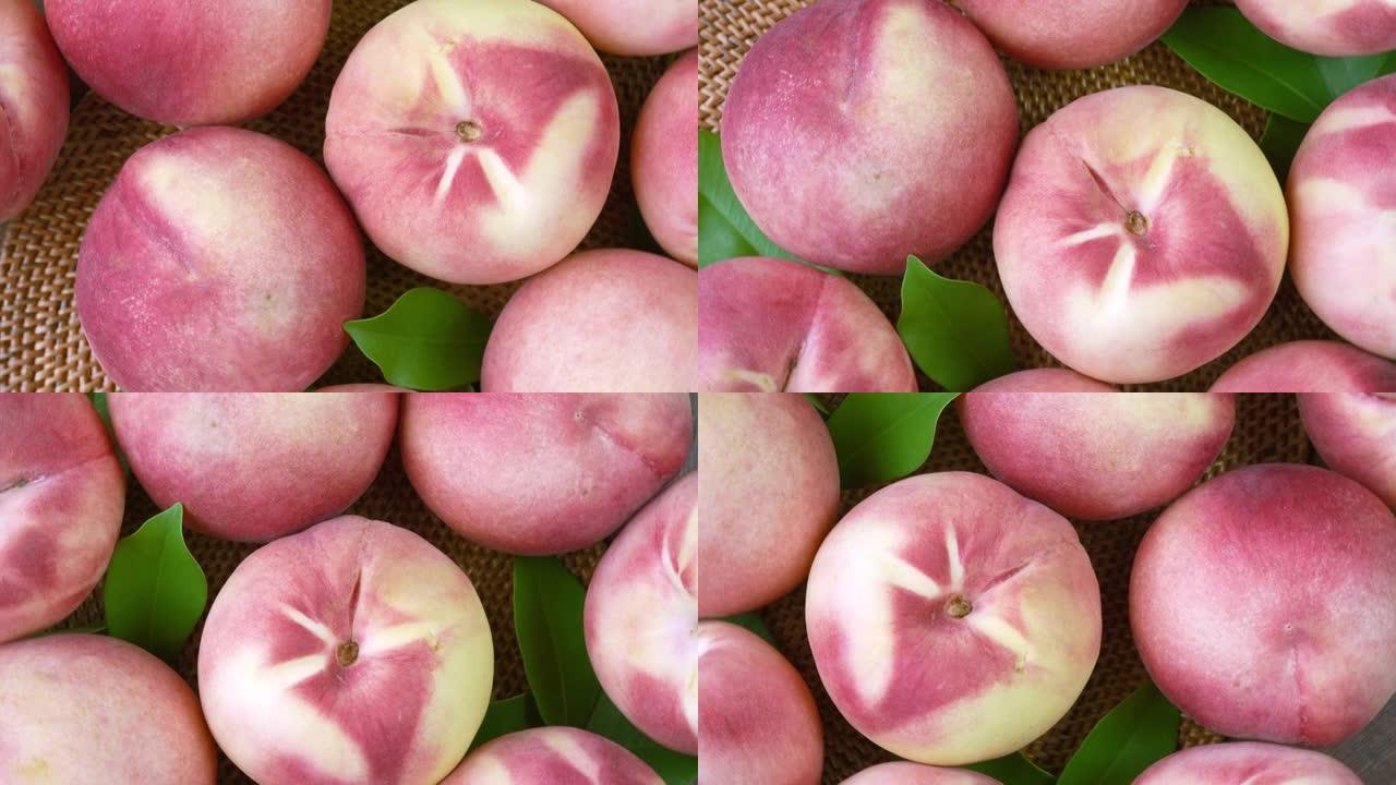 俯视图旋转新鲜的桃子与切片特写，白色的桃子放在花园的木桌上的竹席上。