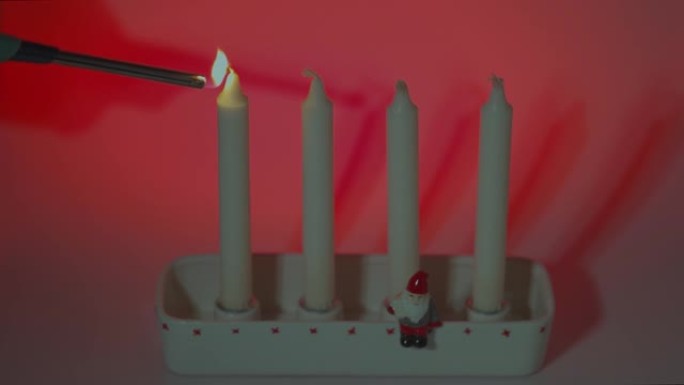近景的人点燃第一支蜡烛在传统的烛台上第一次出现在一个红色的背景。瑞典。