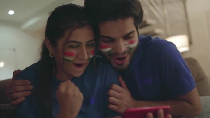 年轻的印度夫妇在手机上观看和享受板球比赛