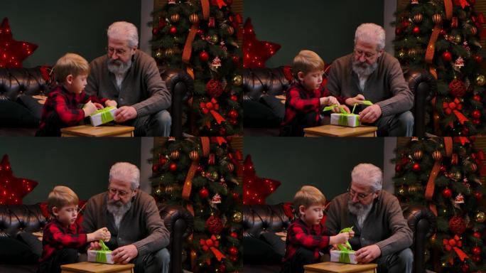 优雅的老人和小男孩打包礼品盒并系蝴蝶结。祖父和孙子坐在装饰房间的沙发上，靠近一棵发光的圣诞树。家庭度