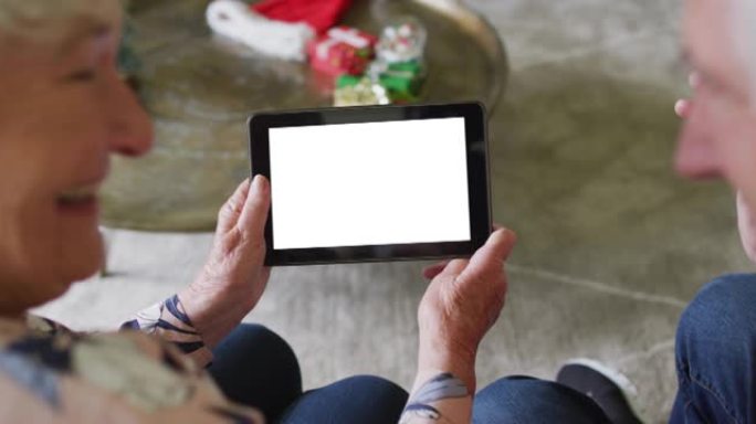 微笑的白人高级夫妇进行平板电脑圣诞节视频通话，在屏幕上复制空间