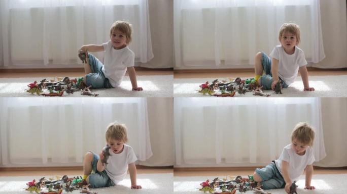 金发孩子，蹒跚学步的男孩，在家玩塑料动物玩具
