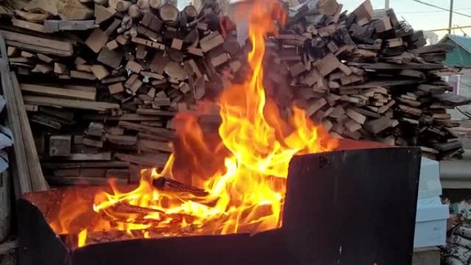 在木柴山的背景下，铁烧烤架中的火焰