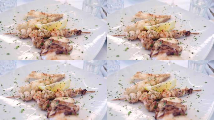 高级厨房美食，豪华餐厅的海鲜白盘。用新鲜欧芹块和柠檬片调味的烤虾和鱿鱼。美味昂贵的海鲜盘