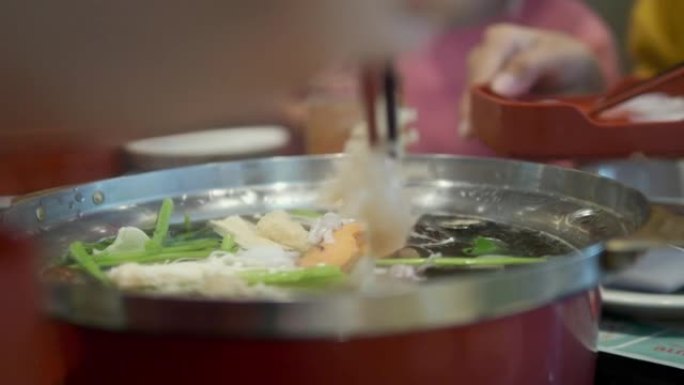 亚洲儿童在餐厅里吃sha锅 (Sukiyaki) 或火锅日本料理，并与家庭，生活方式相结合。