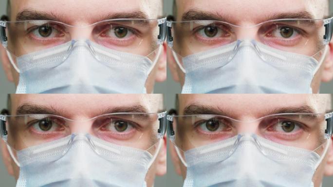 医生的特写镜头，科学家专家戴着医用防护眼镜和口罩，在相机中穿着制服的男性专业化学家的肖像，孤立在灰色