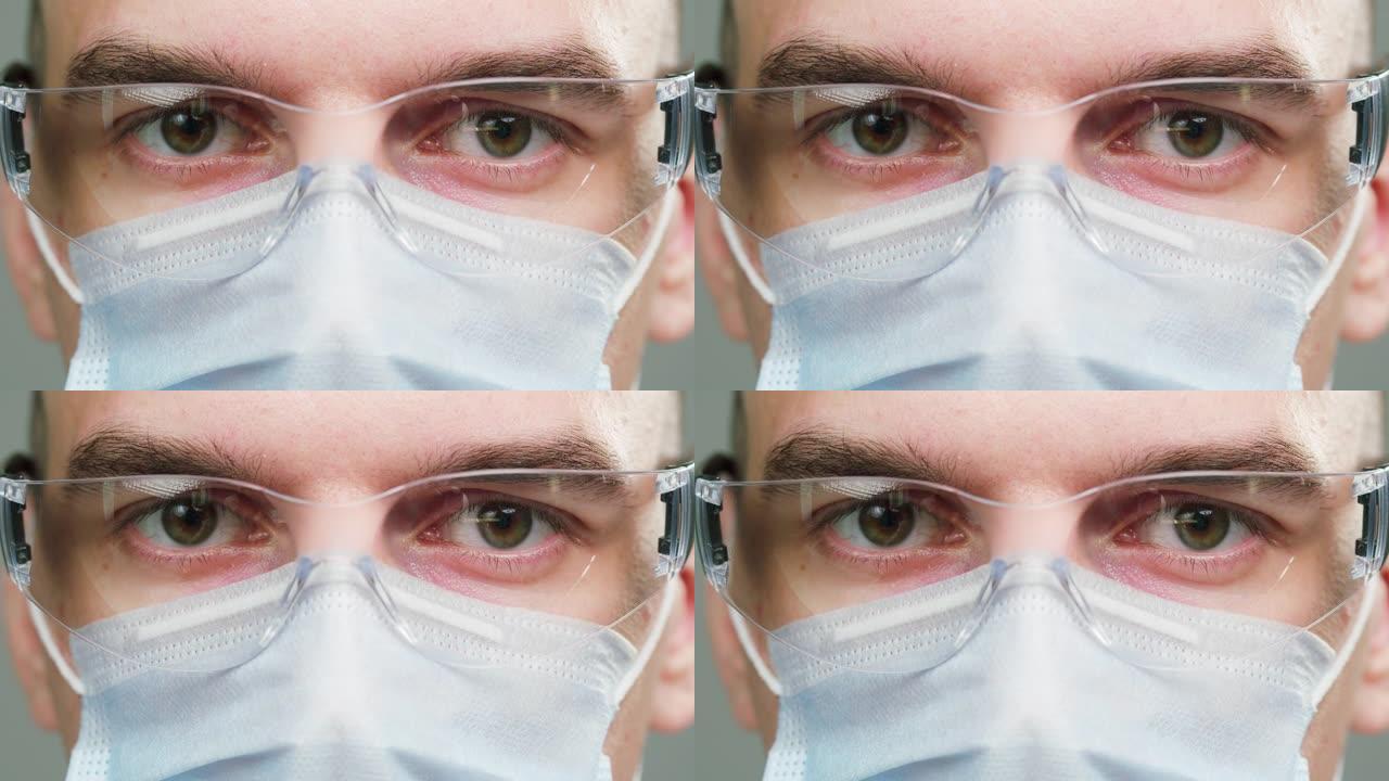 医生的特写镜头，科学家专家戴着医用防护眼镜和口罩，在相机中穿着制服的男性专业化学家的肖像，孤立在灰色