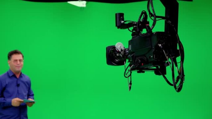 相机起重机jimmy jib在专业的色键工作室跟随播音员。专业人员看起来所有的拍摄设备; 灯，相机，