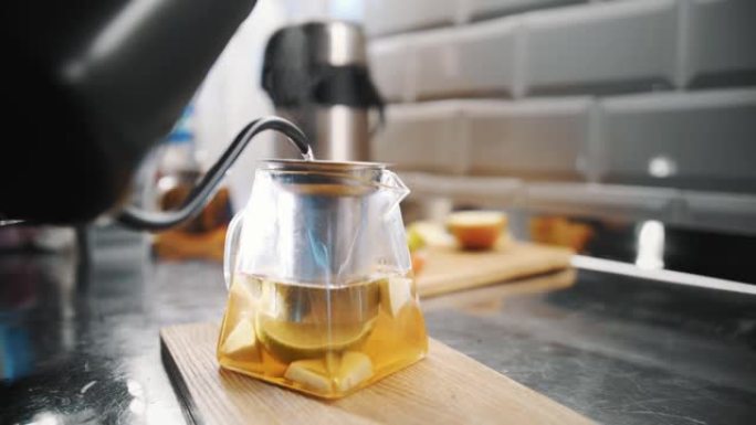 茶饮料。泡茶。特写。用不同的水果片将沸水倒入玻璃茶壶中。特制热果茶饮料的烹调工艺