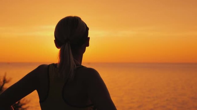 有目的的女运动员在海上看日落，后视