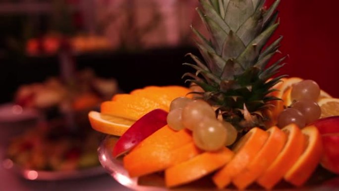 多层托盘上的混合水果排列。显示的水果包括葡萄，西瓜，菠萝，甜瓜，酸橙和其他