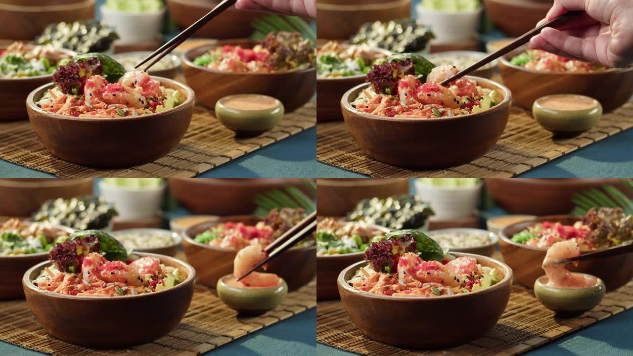 吃poke碗特写，用筷子取虾，蘸酱。由切片蔬菜、鱼和绿色植物制成的传统夏威夷菜肴。健康素食。亚洲素食