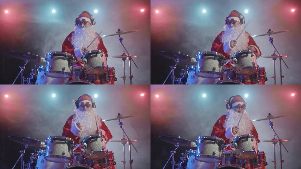 穿着红色服装的圣诞老人留着胡须，戴着滑稽的眼镜，在黑暗的工作室里打鼓，灯光明亮，烟雾缭绕。一个穿着狂