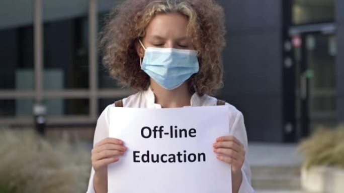 戴医用口罩的女学生举牌线下教育