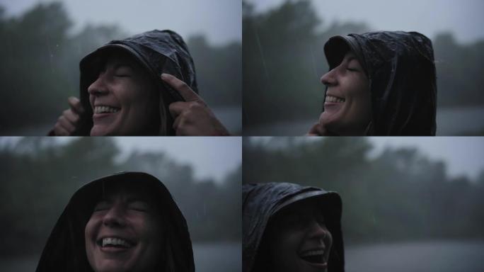 雨中微笑的女人穿着雨衣享受大自然。水滴落在他脸上，女孩很高兴。自然、自由、纯洁的概念...