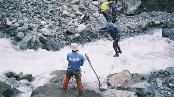 一名游客沿着用登山扣固定的垂直电缆过河。