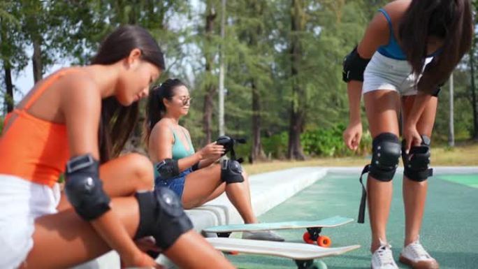 亚洲女子和女朋友在滑板公园滑板前戴安全滑板护膝