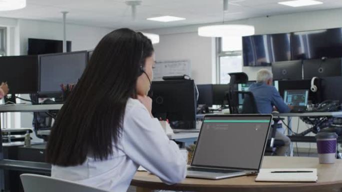 坐在办公桌前的亚洲妇女在笔记本电脑上编码数据