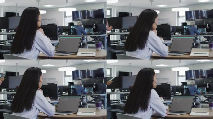 坐在办公桌前的亚洲妇女在笔记本电脑上编码数据