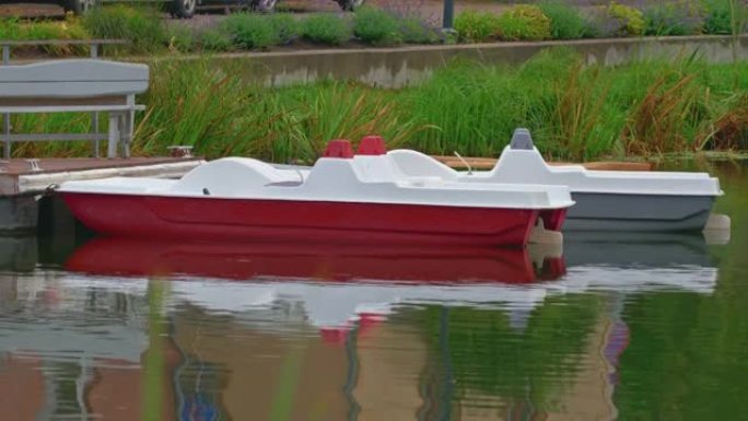 红色和灰色的小船站在码头的水面上