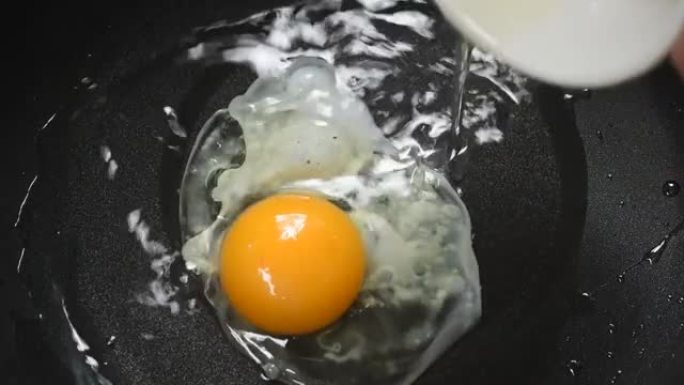 在电锅上从热油杯中倒入煎蛋
