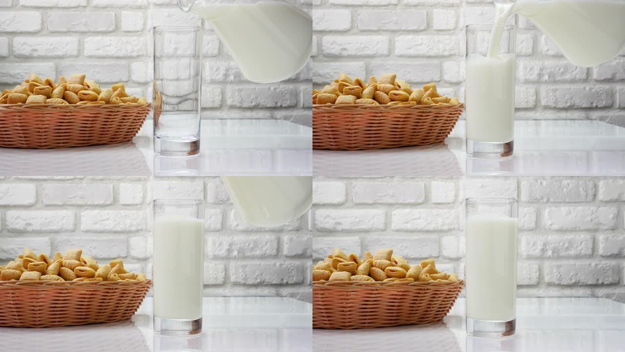 将新鲜的乳制品倒入白色砖墙背景下的玻璃杯中，新鲜的牛奶和糕点放在厨房的桌子上。从水罐里倒牛奶。奶昔