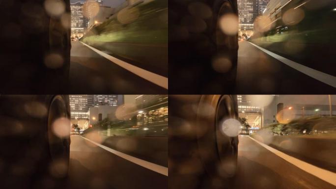 在雨夜开车穿过城市。汽车车轮的特写。