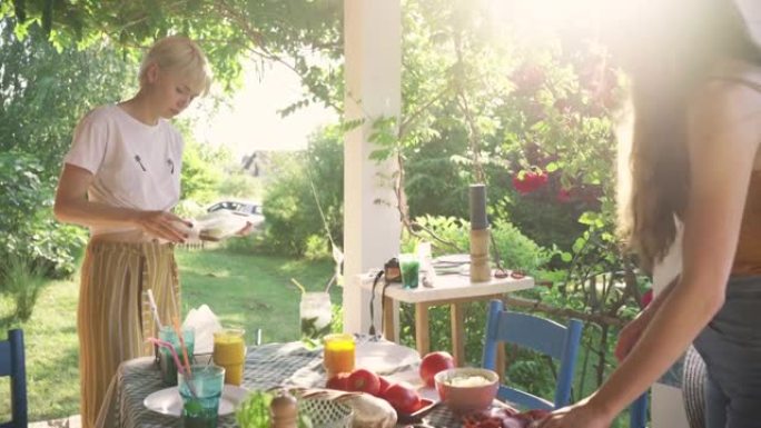 对于花园中的夏季早午餐，女性朋友准备餐桌和foos