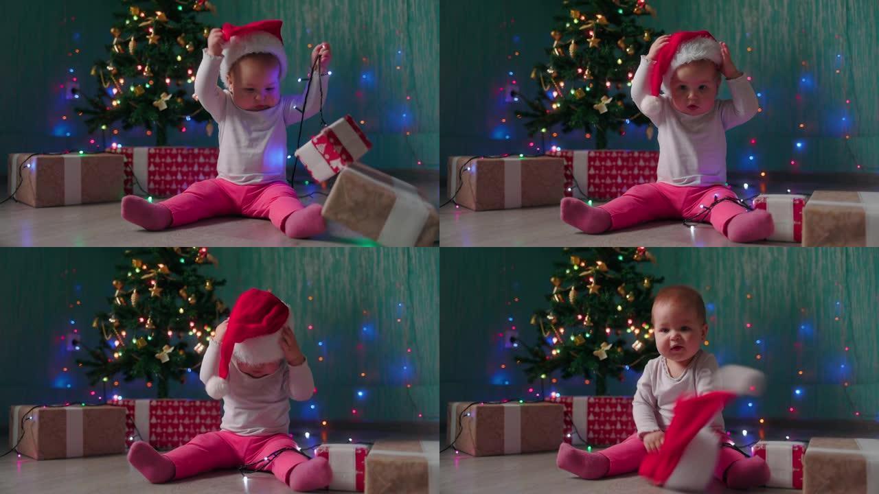 一个有趣的小女孩坐在圣诞树旁，脱下圣诞帽。慢动作。寒假的概念