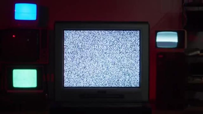 红色霓虹灯背景下的复古旧电视。古老的老式老式电视的组成，带有灰屏，信号接收不良，波纹和干扰，摄影概念