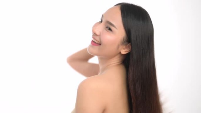 微笑的女人检查和看着她的头发的特写镜头。年轻女性的肖像在白色背景下进行皮肤护理。亚洲女性美容概念