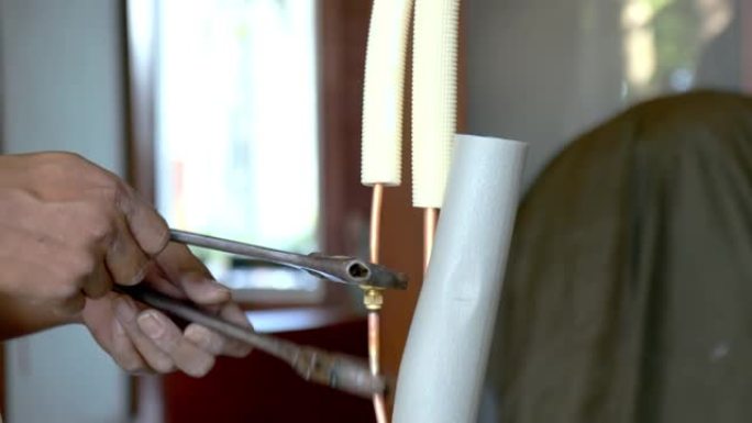 手动特写-亚洲空调技术人员在空调安装过程中使用扭矩扳手将铜管与火炬连接。