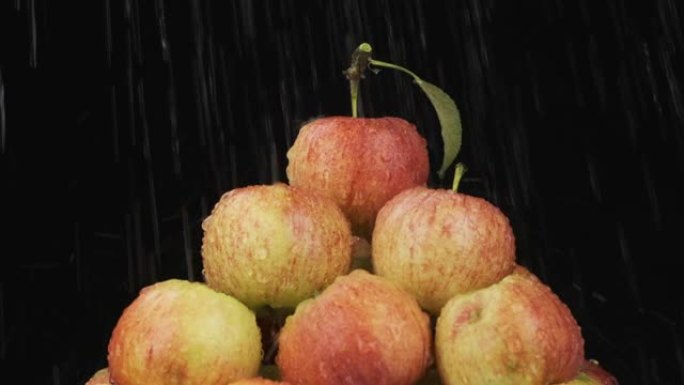 慢动作。雨滴落在一堆苹果上。水果金字塔。