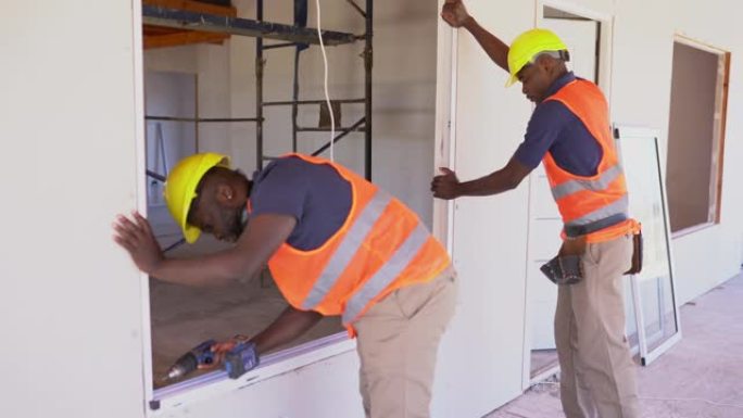非裔美国建筑工人在木结构房屋建造过程中安装窗户