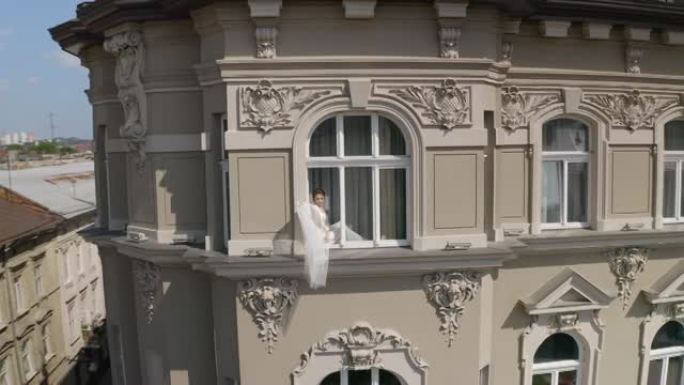 穿着闺房礼服的新娘坐在窗台上婚礼晨间准备穿着睡衣，面纱的女人