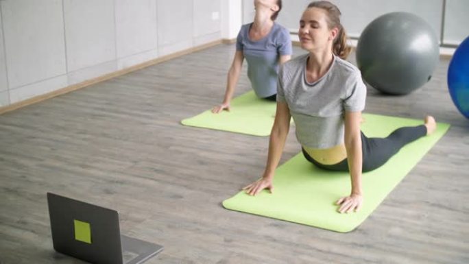 两名健康女性在家与在线老师一起做瑜伽