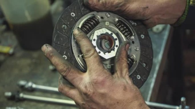 一名汽车修理工正在展示一个旧汽车离合器盘