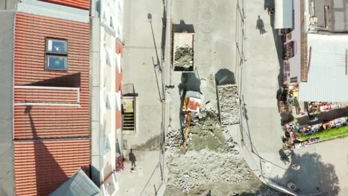 在波兰格但斯克老城区，无人驾驶飞机在挖石铺路石的小型挖掘机上俯视拍摄。修复老城区街道上的铺路石。