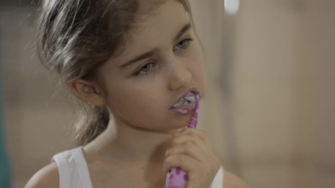 特写肖像年轻的小女孩在浴室刷牙看着镜子反射。日常口腔卫生。快乐肖像可爱的高加索无牙儿童在浴室刷牙。