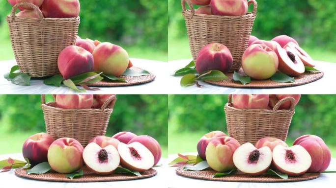 新鲜的桃子在模糊的绿色背景上切成薄片，桃子水果在花园的木桌上的竹篮中。