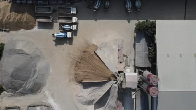 水泥搅拌站，水泥卡车一字排开，成堆的沙子和水泥