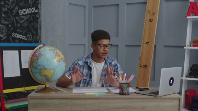 20多岁的非洲裔美国老师与坐在教室里看着笔记本电脑的学生交谈。网校和远程学习理念。