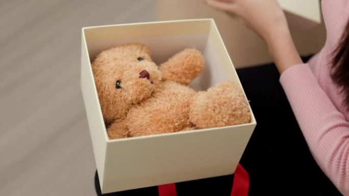 美丽的亚洲女人打开现在的礼品盒，把泰迪熊放在盒子里。年轻快乐可爱的女孩在圣诞节节日庆祝，许多礼品盒坐