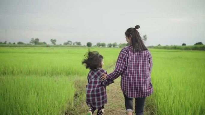 年轻的亚洲母女在绿茵场上奔跑。